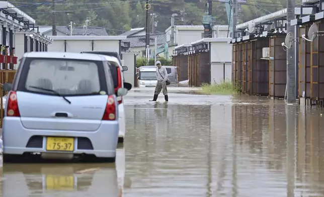 A man wades through a flooded street near temporary housing units installed after the Jan. 1 earthquake in Wajima, Japan, Sunday, Sept. 22, 2024, following heavy rain in central Japan's Noto peninsula area, where a devastating earthquake took place on Jan. 1. (Muneyuki Tomari/Kyodo News via AP)