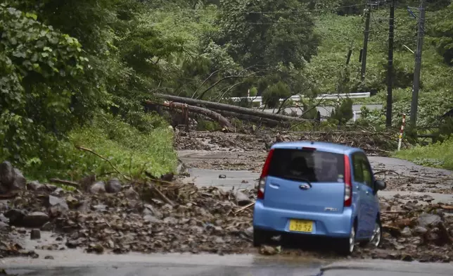 A car is blocked by rocks covering a road, after heavy rain in Wajima, Ishikawa prefecture, Saturday, Sept. 21, 2024. (Kyodo News via AP)