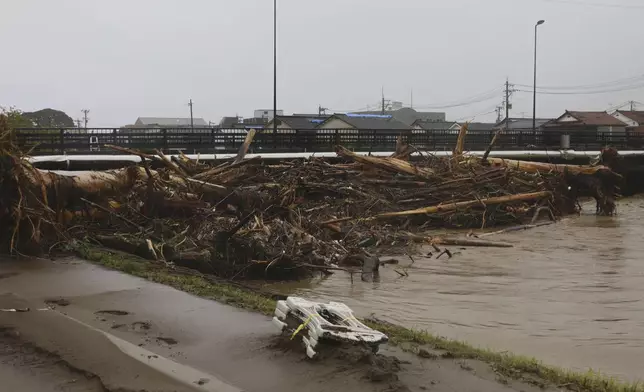 Debris is piled along a bridge over the Kawarada river near the city hall in Wajima, Japan, Sunday, Sept. 22, 2024, following heavy rain in central Japan's Noto peninsula area. (Yasuko Kishimoto/Kyodo News via AP)