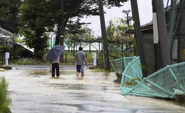 People wade through a partially flooded street in Suzu, Japan, Sunday, Sept. 22, 2024, following heavy rain in central Japan's Noto peninsula area, where a devastating earthquake took place on Jan. 1. (Kasumi Fukudome/Kyodo News via AP)