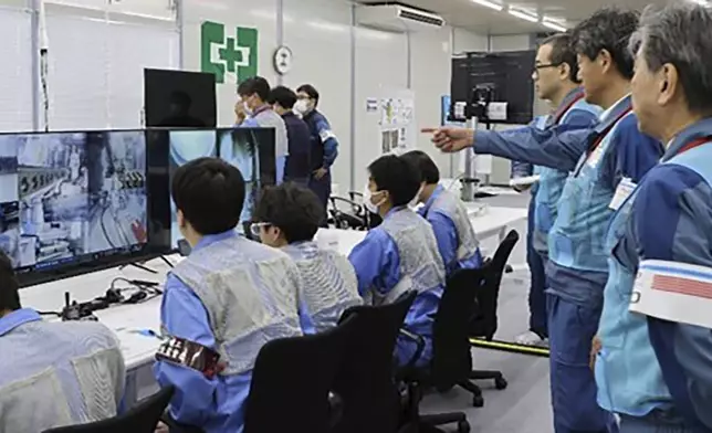 In this photo released by Tokyo Electric Power Company Holdings (TEPCO), TEPCO executives observe a mission to retrieve the first sample of melted fuel debris from inside one of three damaged reactors, at an operation room at the Fukushima Daiichi nuclear power plant in Okuma, Fukushima prefecture, northern Japan Tuesday, Sept. 10, 2024.(Tokyo Electric Power Company Holdings via AP)