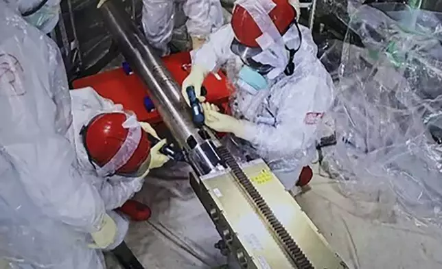 In this photo released by Tokyo Electric Power Company Holdings (TEPCO), monitoring workers rearrange the push-in pipes, at the Fukushima Daiichi nuclear power plant in Okuma, Fukushima prefecture, northern Japan Tuesday, Sept. 10, 2024. An extendable robot began on Tuesday a two-week mission to retrieve the first sample of melted fuel debris from inside one of three damaged reactors at the nuclear power plant.(Tokyo Electric Power Company Holdings via AP)