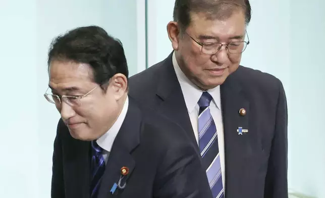 Japan's Prime Minister Fumio Kishida, left, walks past the newly elected head of the Liberal Democratic Party Shigeru Ishiba after the party's leadership election at its headquarters in Tokyo. on Sept. 27, 2024. (Japan Pool/Kyodo News via AP)