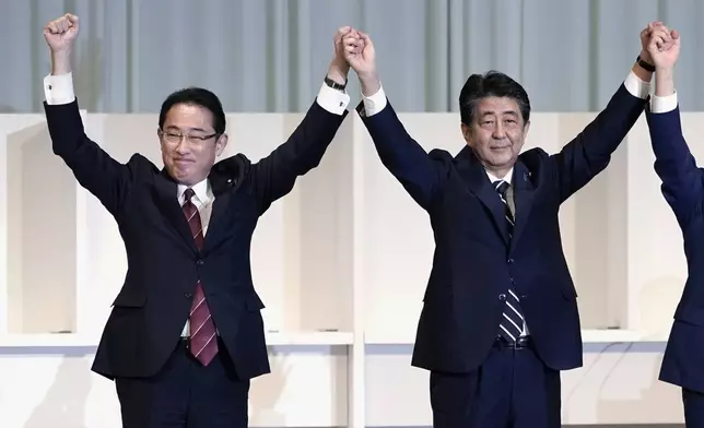 FILE - Former Japan's Foreign Minister Fumio Kishida, left, and Prime Minister Shinzo Abe celebrate after Chief Cabinet Secretary Yoshihide Suga was elected as new head of Japan's ruling party at the Liberal Democratic Party's (LDP) leadership election in Tokyo on Sept. 14, 2020. (AP Photo/Eugene Hoshiko, Pool, File)