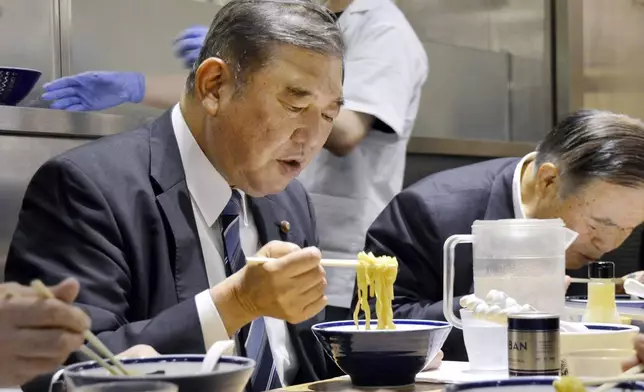 Shigeru Ishiba and other LDP members eat a bowl of ramen noodles at a ramen shop in Tokyo, May 21, 2024. (Kyodo News via AP)