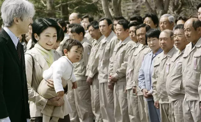 FILE - Japan's Prince Akishino, left, and his wife Princess Kiko, carrying their son Prince Hisahito, are welcomed by the staff of an imperial ranch in Takanezawa, north of Tokyo, March 28, 2008. (AP Photo/Koji Sasahara, File)