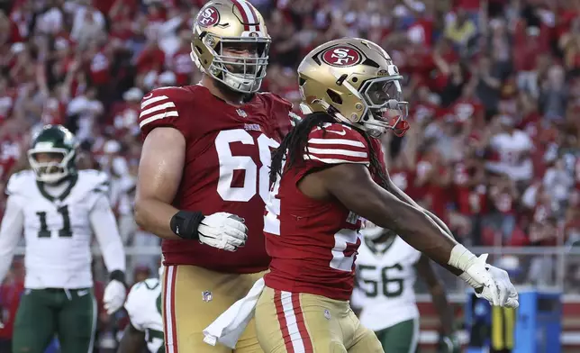 San Francisco 49ers running back Jordan Mason, right, celebrates with offensive tackle Colton McKivitz, front left, after scoring against the New York Jets during the second half of an NFL football game in Santa Clara, Calif., Monday, Sept. 9, 2024. (AP Photo/Jed Jacobsohn)