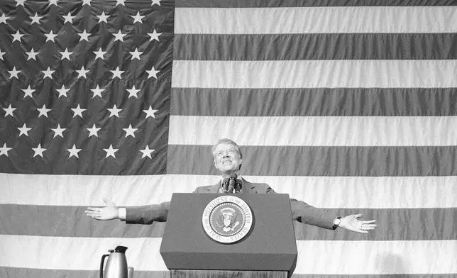 FILE - President Jimmy Carter acknowledges the applause of about 1,100 people gathered in the Elk City High School gym for a town meeting in Elk City, Okla., March 24, 1979. (AP Photo, File)