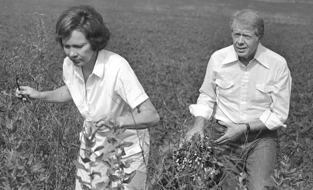 FILE - President Jimmy Carter carries a peanut plant as he follows his wife Rosalynn from the field at their Webster County, Ga., farm on August 19, 1978. (AP Photo/Jim Wells, File)