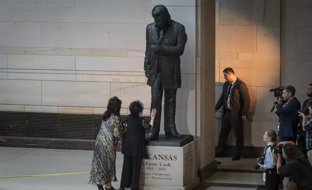 Joanne Cash, second from left, sister of Johnny Cash, touches his statue at the unveiling of a bronze statue of singer Johnny Cash, created by Little Rock sculptor Kevin Kresse, in Emancipation Hall at the Capitol in Washington, Tuesday, Sept. 24, 2024. (AP Photo/Ben Curtis)