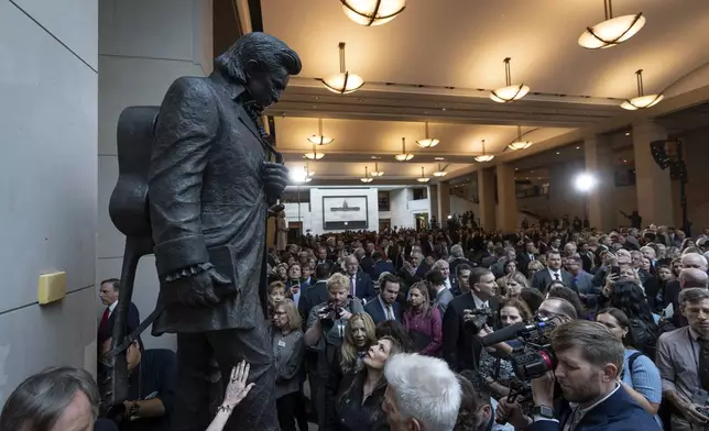 People crowd around after the unveiling of a bronze statue of singer Johnny Cash, created by Little Rock sculptor Kevin Kresse, in Emancipation Hall at the Capitol in Washington, Tuesday, Sept. 24, 2024. (AP Photo/Ben Curtis)