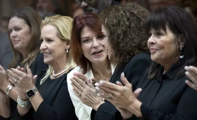 From left to right, Arkansas Gov. Sarah Huckabee Sanders, Arkansas Lt. Gov. Leslie Rutledge, and daughters of Johnny Cash, Rosanne Cash, Tara Cash Schwoebel, and Kathy Cash, listen to a band play his song "I Walk the Line" at the unveiling of a bronze statue of singer Johnny Cash, in Emancipation Hall at the Capitol in Washington, Tuesday, Sept. 24, 2024. (AP Photo/Ben Curtis)