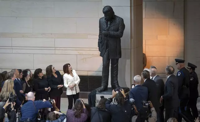 Daughter Rosanne Cash, center left, accompanied by other family members, looks up at the unveiling of a bronze statue of singer Johnny Cash, created by Little Rock sculptor Kevin Kresse, in Emancipation Hall at the Capitol in Washington, Tuesday, Sept. 24, 2024. (AP Photo/Ben Curtis)