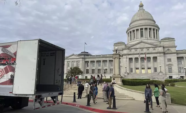 A crowd gathers to watch a tractor trailer holding a statue of Johnny Cash, depart from the Arkansas Capitol in Little Rock, Ark., Thursday, Sept. 5, 2024. (AP Photo/Andrew DeMillo)