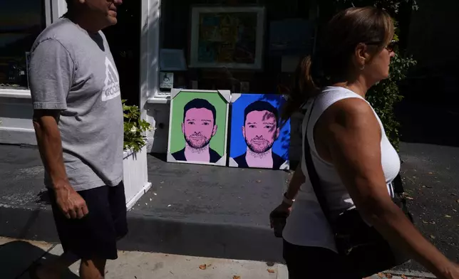 People walk past paintings of Justin Timberlake outside a gallery, Friday, Sept. 13, 2024, in Sag Harbor, N.Y. (AP Photo/Pamela Smith)