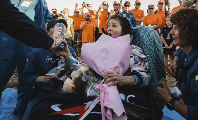 In this photo released by Roscosmos space corporation, NASA astronaut Tracy Dyson is gifted with flowers and a Russian traditional Matryoshka wooden doll depicting her shortly after the landing of the Russian Soyuz MS-25 space capsule carrying NASA astronaut Tracy Dyson, Roscosmos cosmonauts Oleg Kononenko and Nikolai Chub, south-east of the Kazakh town of Zhezkazgan, Kazakhstan, Monday, Sept. 23, 2024. (Ivan Timoshenko, Roscosmos space corporation via AP)