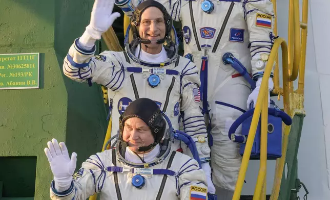 In this image provided by NASA, Expedition 72 crew members: Roscosmos cosmonaut Ivan Vagner, top, NASA astronaut Don Pettit, center, and Roscosmos cosmonaut Alexey Ovchinin, wave farewell prior to boarding the Soyuz MS-26 spacecraft for launch, Wednesday, Sept. 11, 2024 at the Baikonur Cosmodrome in Kazakhstan. Launch of the Soyuz rocket will send the trio on a mission to the International Space Station. (Bill Ingalls/NASA via AP)