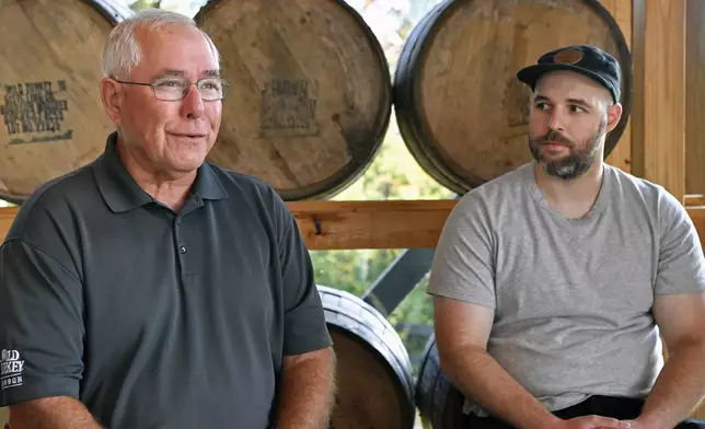 As his son Bruce Russell, right, looks on, Eddie Russell, master distiller, and son of 89-year-old Jimmy Russell, the "Buddha of Bourbon" talks about having three generations of the Russell family involved in the bourbon industry at the Wild Turkey Distillery in Lawrenceburg, Ky., Wednesday, Aug. 28, 2024. (AP Photo/Timothy D. Easley)