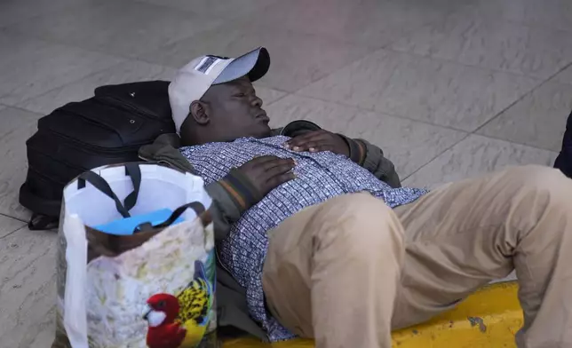 A stranded passenger takes a nap as he wait for delayed flight out of JKIA airport in Nairobi, Kenya Wednesday, Sep. 11, 2024. Hundreds of workers at Kenya's main international airport demonstrated on Wednesday against a planned deal between the government and a foreign investor. Planes have remained grounded, with hundreds of passengers stranded at the airport. (AP Photo/Brian Inganga)