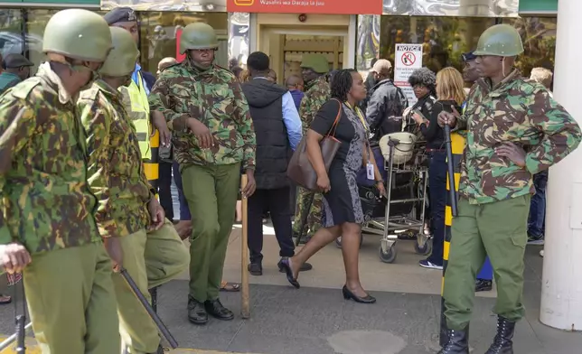 Kenya anti riot police stand guard as stranded passengers wait for their delayed flights out of JKIA airport after flights were grounded following workers’ protesting a planned deal between the government and a foreign investor, in Nairobi, Kenya, Wednesday, Sept. 11, 2024. (AP Photo/Brian Inganga)