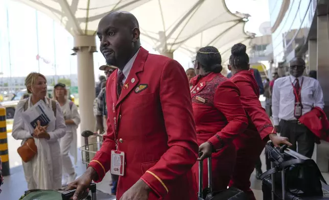 Kenya airways flight attendants queue alongside stranded passengers waiting for their delayed flights out of JKIA airport after flights were grounded following workers’ protesting a planned deal between the government and a foreign investor, in Nairobi, Kenya, Wednesday, Sept. 11, 2024. (AP Photo/Brian Inganga)