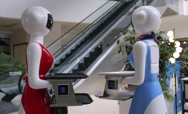 Robotic waiters stand at the Robot Cafe in Nairobi, Kenya Thursday, Aug. 29, 2024. The three robots, christened Claire, R24 and Nadia, are not programmed to have a full conversation with customers, but they can say "Your order is ready, Welcome" then people have to press an exit button after picking up their food from the tray. (AP Photo/Brian Inganga)