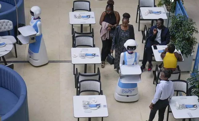 Robotic waiters serve customers at Robot Cafe in Nairobi, Kenya Thursday, Aug. 29, 2024. Robot Café, is first of a kind in Nairobi and East Africa, where three robots glide among human waiters serving food to mesmerized customers. (AP Photo/Brian Inganga)