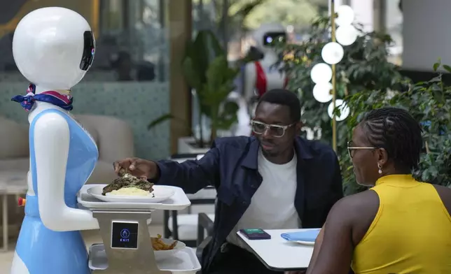 Robotic waiter Claire, delivers an order to customers at the Robot Cafe in Nairobi, Kenya Thursday, Aug. 29, 2024. The three robots, christened Claire, R24 and Nadia, are not programmed to have a full conversation with customers, but they can say "Your order is ready, Welcome" then people have to press an exit button after picking up their food from the tray. (AP Photo/Brian Inganga)