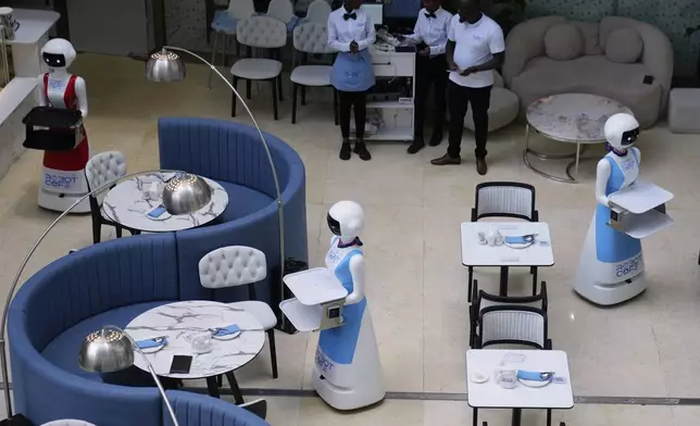 Robotic waiters stand at Robot Cafe in Nairobi, Kenya Thursday, Aug. 29, 2024. The three robots, christened Claire, R24 and Nadia, are not programmed to have a full conversation with customers, but they can say "Your order is ready, Welcome" then people have to press an exit button after picking up their food from the tray. (AP Photo/Brian Inganga)