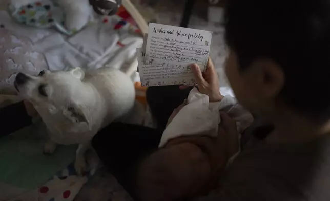 Robyn Joy Park reads a card offering best wishes and advice for her daughter, Rae, at her home in Pasadena, Calif., Friday, April 19, 2024. The card was written by the daughter of Michaela Dietz. Park and Dietz were both adopted as children from South Korea, and later learned their identities were switched with other children. (AP Photo/Jae C. Hong)