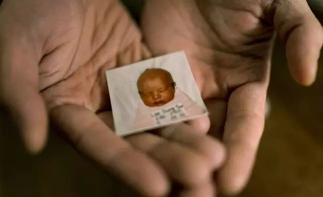 Robert Calabretta holds his baby photo from before he was adopted out of South Korea to a family in the United States, Thursday, Feb. 15, 2024, at his apartment in New York. (AP Photo/David Goldman)