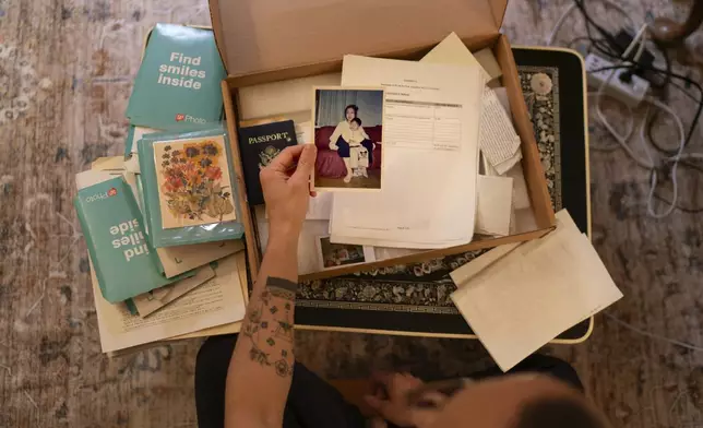 Robert Calabretta holds a picture of his biological mother and brother while sifting through family mementos at his apartment, Thursday, Feb. 15, 2024, in New York. After Calabretta was adopted as a baby to an American family, hospital officials told his mother to assume he had died. (AP Photo/David Goldman)