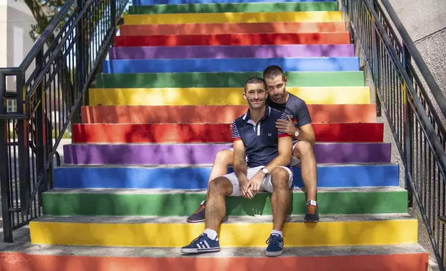 Stefan Arestis, left, with Sebastien Chaneac appear on rainbow-painted stairs in Tampa, Fla., in 2019. Together, the two write the travel blog The Nomadic Boys. (The Nomadic Boys via AP)