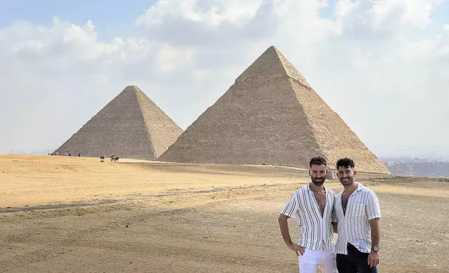 This 2023 photo shows Stefan Arestis, right, and Sebastien Chaneac, at the Pyramids in Egypt. The two are globetrotters who run the LGBTQ+-focused travel blog The Nomadic Boys. They published a travel guide this year, “Out in the World: The Gay Guide to Travelling with Pride.” (The Nomadic Boys via AP)