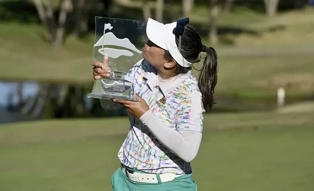 Jasmine Suwannapura, of Thailand, celebrates with her trophy after winning the LPGA Walmart NW Arkansas Championship golf tournament, Sunday, Sept. 29, 2024, in Rogers, Ark. (AP Photo/Michael Woods)