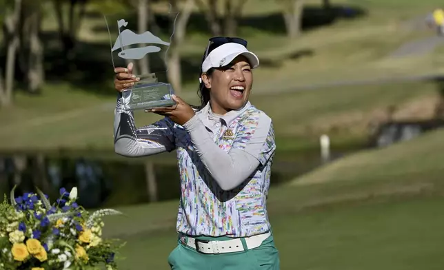 Jasmine Suwannapura, of Thailand, celebrates with her trophy after winning the LPGA Walmart NW Arkansas Championship golf tournament, Sunday, Sept. 29, 2024, in Rogers, Ark. (AP Photo/Michael Woods)