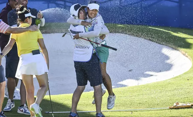 Jasmine Suwannapura, of Thailand, celebrates with her caddie and husband Mike Thomas after winning the LPGA Walmart NW Arkansas Championship golf tournament, Sunday, Sept. 29, 2024, in Rogers, Ark. (AP Photo/Michael Woods)