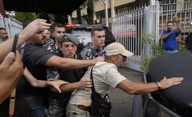 Protesters confront the police convoy transporting Riad Salameh, the former governor of Lebanon's Central Bank, upon his arrival at the court building in Beirut, Lebanon, Monday, Sept. 9, 2024. (AP Photo/Hussein Malla)