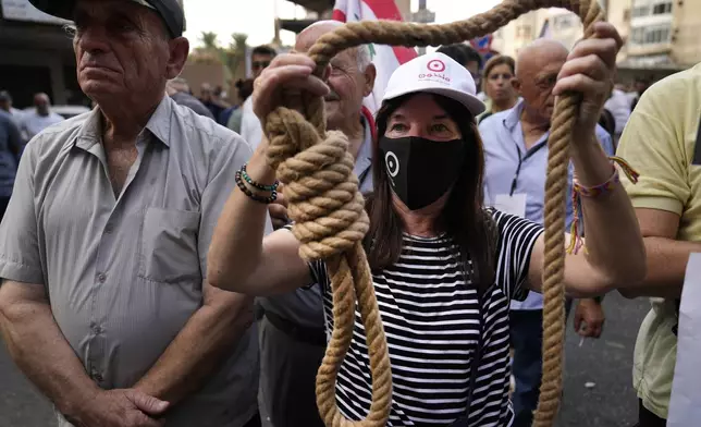 A protester holds a mock noose, as she protests outside the court building against Riad Salameh the former governor of Lebanon's Central Bank, in Beirut, Lebanon, Monday, Sept. 9, 2024. (AP Photo/Hussein Malla)