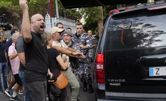 Protesters try to confront the police convoy transporting Riad Salameh, the former governor of Lebanon's Central Bank, upon his arrival at the court building in Beirut, Lebanon, Monday, Sept. 9, 2024. (AP Photo/Hussein Malla)