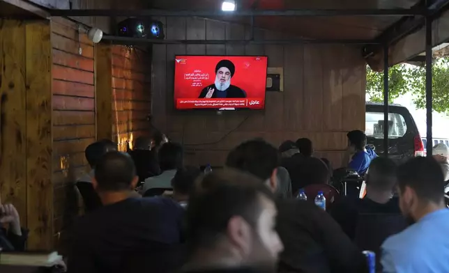 People watch the speech of Hezbollah leader Hassan Nasrallah on a tv screen as they sit in a cafe in the southern suburbs of Beirut, Thursday, Sept. 19, 2024. (AP Photo/Hassan Ammar)