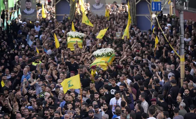 Hezbollah members carry the coffins of two of their comrades who were killed on Wednesday when a handheld device exploded, during a funeral procession in the southern suburbs of Beirut, Thursday, Sept. 19, 2024. (AP Photo/Hussein Malla)