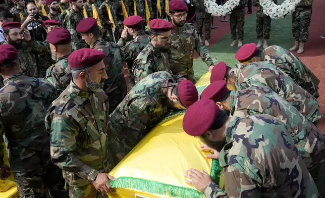 Hezbollah members mourn over the coffins of two of their comrades who were killed on Wednesday when a handheld device exploded, during a funeral procession in the southern suburbs of Beirut, Thursday, Sept. 19, 2024. (AP Photo/Hussein Malla)