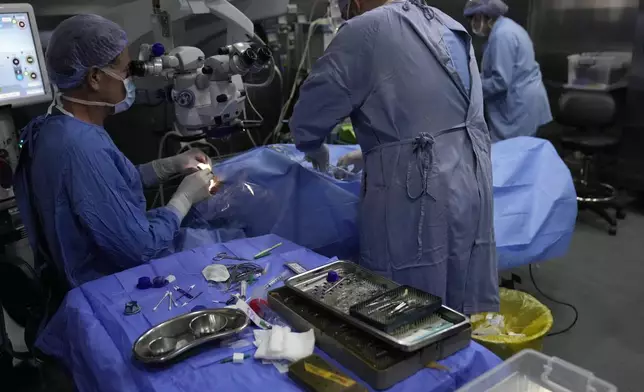 Elias Jaradeh, a legislator and an ophthalmologist, left, who has conducted dozens of operation for victims of this week's attack in Lebanon, makes an eye surgery operation for a man who was injured in the explosion of one of the handheld devices, at the Eye Specialist hospital, in Beirut, Lebanon, Friday, Sept. 20, 2024. (AP Photo/Hussein Malla)