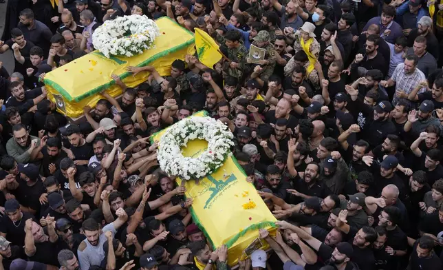 Hezbollah members carry the coffins of two of their comrades who were killed on Wednesday when a handheld device exploded, during a funeral procession in the southern suburbs of Beirut, Thursday, Sept. 19, 2024. (AP Photo/Hussein Malla)