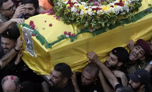 FILE - Hezbollah fighters carry one of the coffins of four fallen comrades who were killed Tuesday after their handheld pagers exploded, in the southern suburb of Beirut, Wednesday, Sept. 18, 2024. (AP Photo/Bilal Hussein, File)