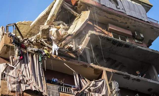 Residents check a partially destroyed building at the site of an Israeli airstrike in Beirut's southern suburbs, Tuesday, Sept. 24, 2024. (AP Photo/Hassan Ammar)