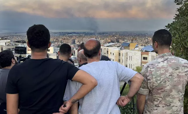 Lebanese citizens watch smoke rise from Israeli airstrikes in the southern suburbs of Beirut, Lebanon, Saturday, Sept. 28, 2024. (AP Photo/Hussein Malla)