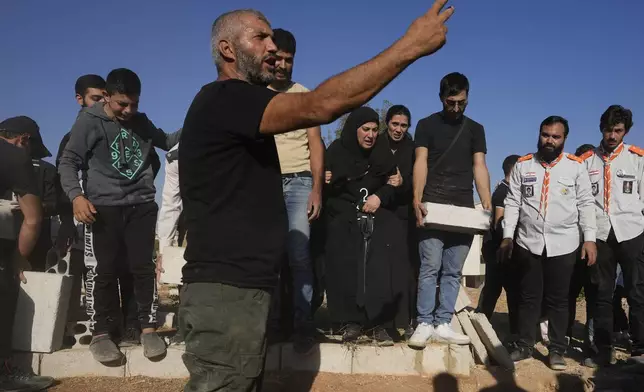 Mourners bury the bodies of their relatives, killed in Israeli airstrikes in the village of Karak, Bekaa Valley, eastern Lebanon, Friday, Sept. 27, 2024. (AP Photo/Hassan Ammar)