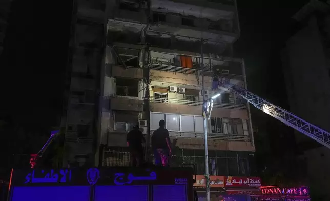 A fire engine ladder extends up a building that was hit in an apparent Israeli airstrike, in central Beirut, Lebanon, early Monday, Sept. 30, 2024. (AP Photo/Bilal Hussein)